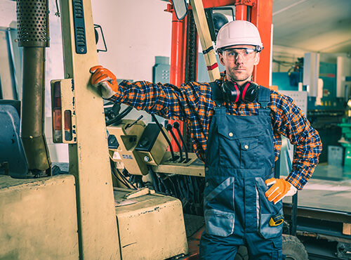 Noise in industrial buildings and workshops A worker with ear defenders stands in a loud factory or workshop.