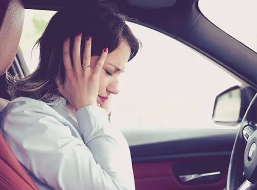 A woman tries to protect herself from noise in the car.