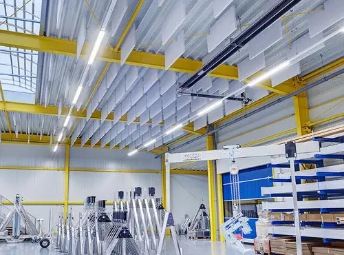 Sound absorbers hang from the ceiling of a factory and reduce noise.