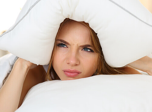 Noise in the home Noise in the home – a young woman closes her ears