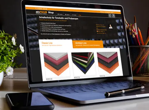 A laptop shows the aixFOAM Online Shop with a selection of sound absorbers and sound insulation products.