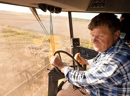 Less noise in agriculture – a worker drives a soundproofed combine harvester.